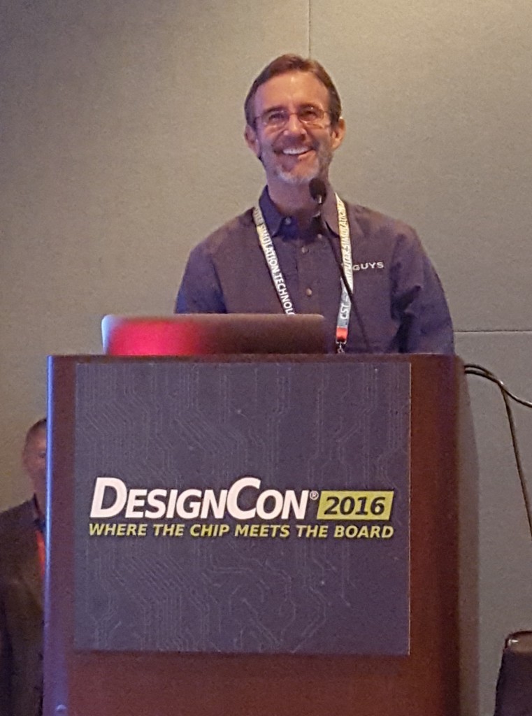 Man with beard standing behind podium labeled DesignCon